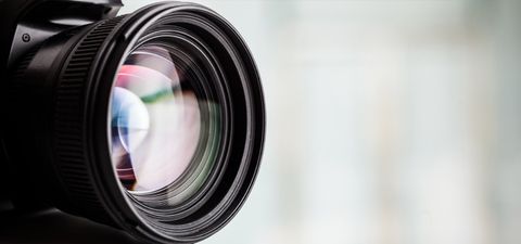 Close-up of a camera lens with coloured reflections in the glass