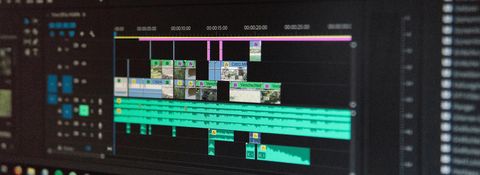 Video editing timeline on a monitor, with video clips on the upper tracks and several audio tracks below