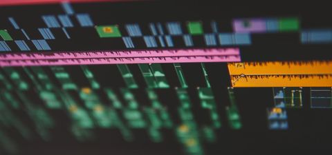 Close-up of a video editing timeline with colourful clips and audio waveforms on a screen